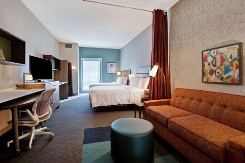 a hotel room with a bed and a couch at Home2 Suites By Hilton Charlotte Uptown in Charlotte
