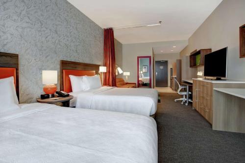 a hotel room with two beds and a flat screen tv at Home2 Suites By Hilton Charlotte Uptown in Charlotte