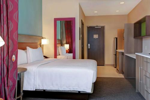 a hotel room with a large white bed and a bathroom at Home2 Suites By Hilton Charlotte Uptown in Charlotte