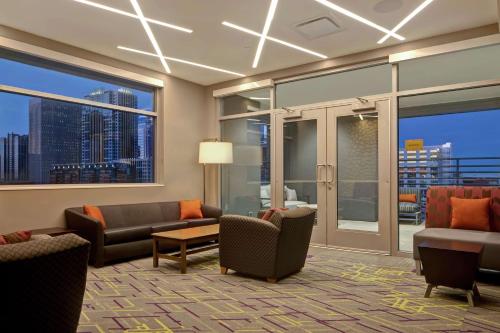 a living room with couches and chairs and windows at Home2 Suites By Hilton Charlotte Uptown in Charlotte