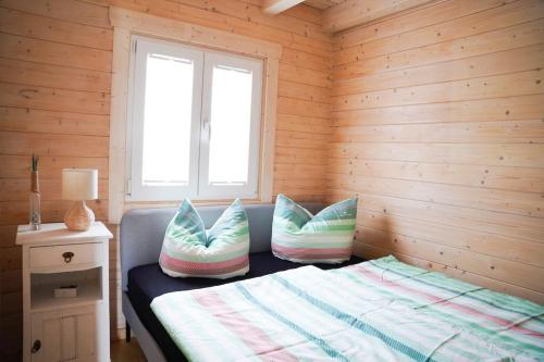 um quarto com uma cama com almofadas e uma janela em Haus am See mit Privatstrand, Kamin und Sauna em Löbnitz