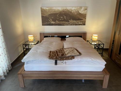 un lit avec des draps blancs et deux lampes sur deux tables dans l'établissement Ferienwohnung Max 1, à Garmisch-Partenkirchen