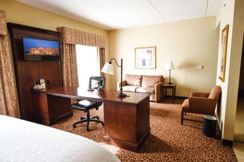 een hotelkamer met een bureau en een bank bij Hampton Inn & Suites Ocala - Belleview in Marion Oaks