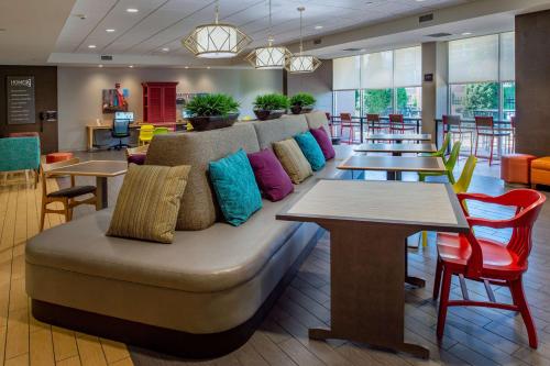 a couch in a restaurant with tables and chairs at Home2 Suites St. Louis / Forest Park in Richmond Heights