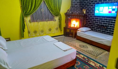 a room with two beds and a fire place at Dar Fadma in Ouarzazate