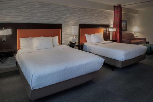 a hotel room with two beds and a chair at Home2 Suites St. Louis / Forest Park in Richmond Heights