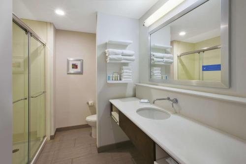 a bathroom with a sink and a mirror and a toilet at Hampton Inn by Hilton Detroit Dearborn, MI in Dearborn