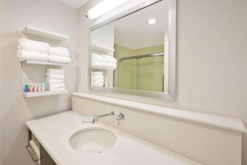 a white bathroom with a sink and a mirror at Hampton Inn by Hilton Detroit Dearborn, MI in Dearborn