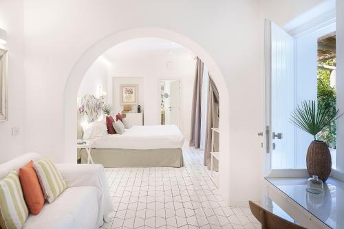 Habitación blanca con cama y sofá en Botania Relais & Spa - The Leading Hotels of the World en Ischia