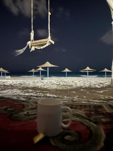 a cup of coffee on the beach with umbrellas at North coast rent Chalet / شاليه للايجار في الساحل in Dawwār Abū Duray‘ah ‘Abd al Karīm