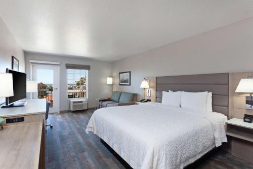 ein Hotelzimmer mit einem großen Bett und einem Stuhl in der Unterkunft Hampton Inn & Suites Hermosa Beach in Hermosa Beach