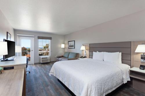 um quarto de hotel com uma cama grande e uma cadeira em Hampton Inn & Suites Hermosa Beach em Hermosa Beach