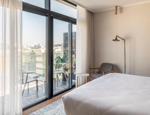 a bedroom with a bed and a large window at Jo Shtibel Tel-Aviv in Tel Aviv