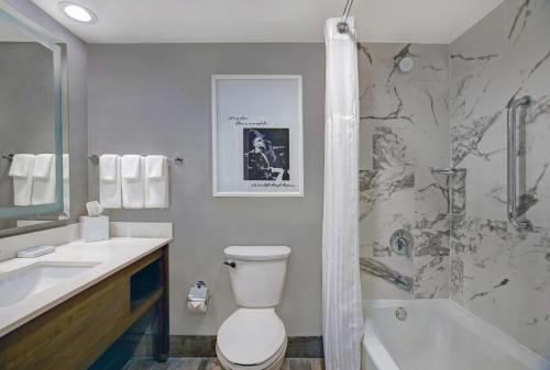 a bathroom with a toilet and a sink and a tub at Hilton Peachtree City Atlanta Hotel & Conference Center in Peachtree City