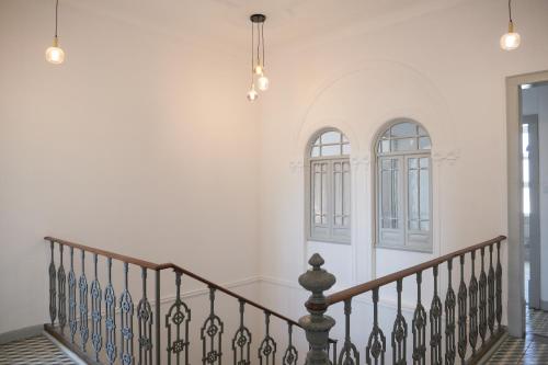 un corridoio con una scala con pareti e finestre bianche di A Janela do Palacete a Reguengos de Monsaraz