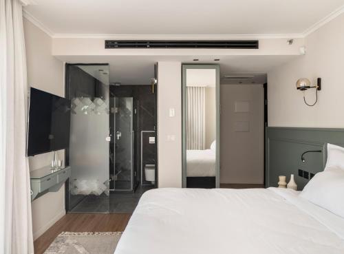 a bedroom with a white bed and a large mirror at Jo Shtibel Tel-Aviv in Tel Aviv