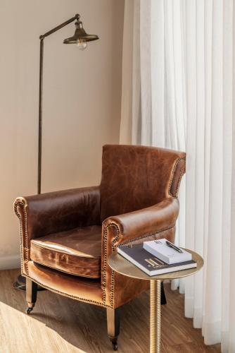 a brown leather chair with a table in a room at Jo Shtibel Tel-Aviv in Tel Aviv
