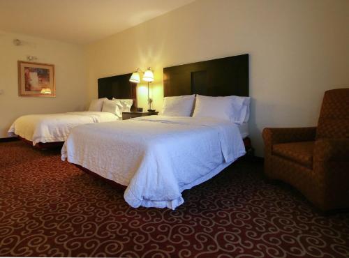 a hotel room with two beds and a chair at Hampton Inn Kingston in Kingston