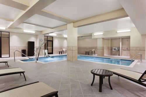 a pool in a hotel with tables and chairs at Hilton Garden Inn Rochester Downtown, NY in Rochester