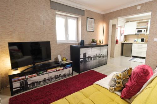 sala de estar con sofá y TV de pantalla plana en Perafita Yellow House - EcoHostPT en Perafita