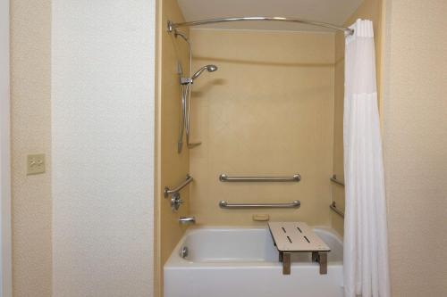 a bathroom with a bath tub with a bench next to it at Hampton Inn London-North, Ky in London