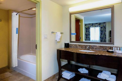 uma casa de banho com um lavatório, uma banheira e um espelho. em Hampton Inn & Suites - Fort Pierce em Fort Pierce