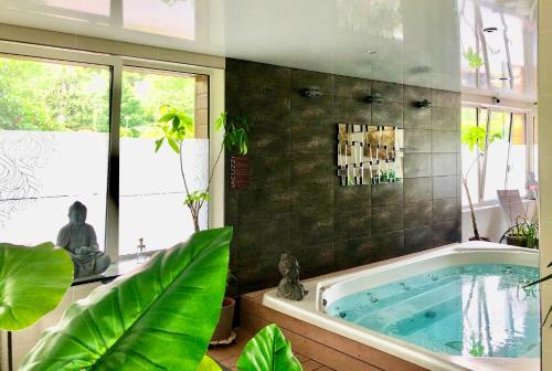- une grande salle de bains pourvue d'une baignoire avec des plantes dans l'établissement Mobile Home Auvergne, à Besse-et-Saint-Anastaise