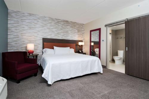 Home2 Suites By Hilton Roswell, Ga في روزويل: غرفة نوم بسرير كبير وكرسي احمر