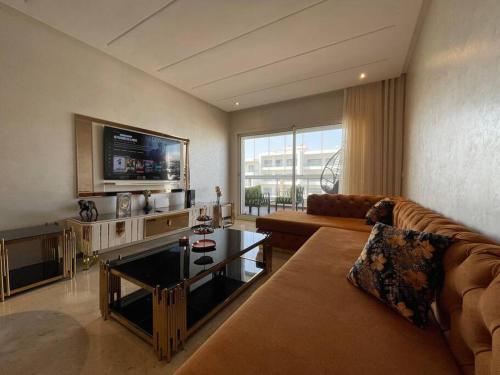 een woonkamer met een bank en een tv bij Appartement de luxe à peninsula in Casablanca