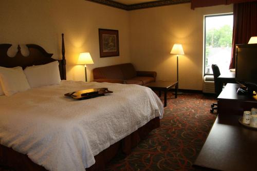 Habitación de hotel con cama, sofá y TV en Hampton Inn Stroudsburg Poconos, en Stroudsburg