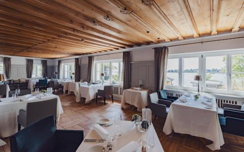 un restaurante con mesas y sillas blancas y ventanas en Hotel Caraleon en Wasserburg