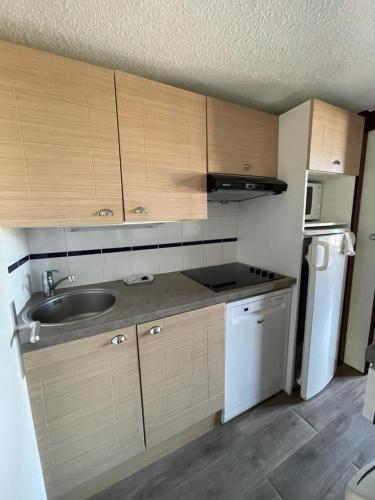 une cuisine avec des armoires en bois, un évier et un réfrigérateur dans l'établissement Vue capitainerie, à Arzon