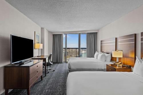 a hotel room with two beds and a flat screen tv at DoubleTree by Hilton Atlantic Beach Oceanfront in Atlantic Beach