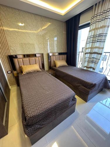 two beds sitting in a room with a window at modern 2bedroom for rent Abdoun in Amman