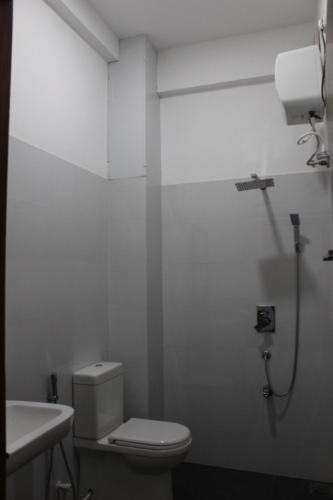 a white bathroom with a toilet and a sink at Windy Hanthana in Kandy