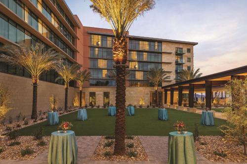 a rendering of a hotel courtyard with tables and palm trees at Hilton North Scottsdale At Cavasson in Scottsdale