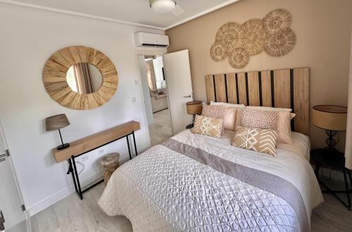ein Schlafzimmer mit einem Bett und einem Spiegel an der Wand in der Unterkunft Luxurious Frontline Golf Villa on Mar Menor Golf in Torre-Pacheco