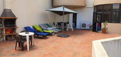 een patio met stoelen en tafels en een parasol bij Beira Mar Apartment in Portimão