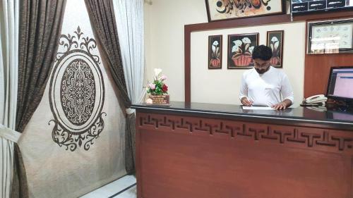 a man standing at a reception desk in a hotel room at Hotel Imperial Karachi in Karachi