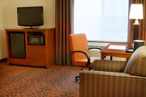 a hotel room with a tv and a chair and a desk at Hampton Inn Bangor in Bangor
