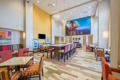 a dining room with tables and chairs and a large screen at Hampton Inn & Suites Phoenix - East Mesa in Gilbert in Gilbert