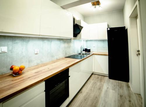 a kitchen with white cabinets and a wooden counter top at LOFTY APARTAMENTY Namysłów I in Namysłów
