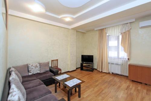 LUXURY Apartment in Yerevan, CENTRE في يريفان: غرفة معيشة مع أريكة وتلفزيون