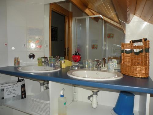 uma casa de banho com 2 lavatórios e uma bancada azul em GITE LES 1000 FLEURS em Souteyros