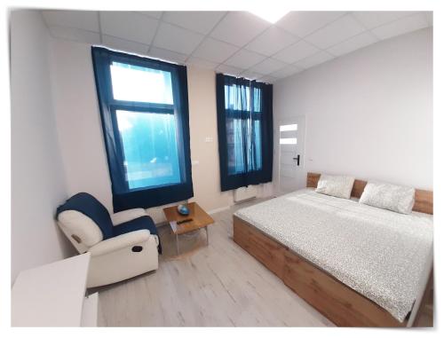 1 dormitorio con 1 cama, 1 silla y ventanas en SouvenirAppart Sienkiewicza, en Bydgoszcz