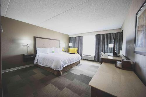 a hotel room with a bed and a large window at Hampton Inn & Suites by Hilton Bolton in Bolton