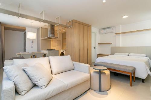 Xtay Soho Florianópolis في فلوريانوبوليس: غرفة معيشة مع أريكة بيضاء وسرير