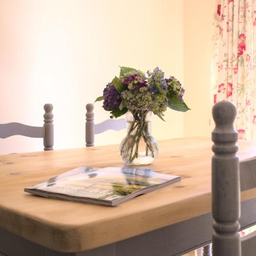 um vaso de flores sentado em cima de uma mesa em Meadowbrook House em Halwell