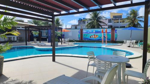 a swimming pool with chairs and a table and a table and chairs at Hotel Enseada dos Corais in Cabo de Santo Agostinho