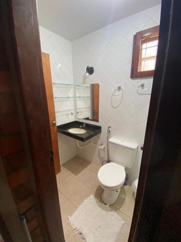 a bathroom with a white toilet and a sink at Casa Paraíso in Gravatá